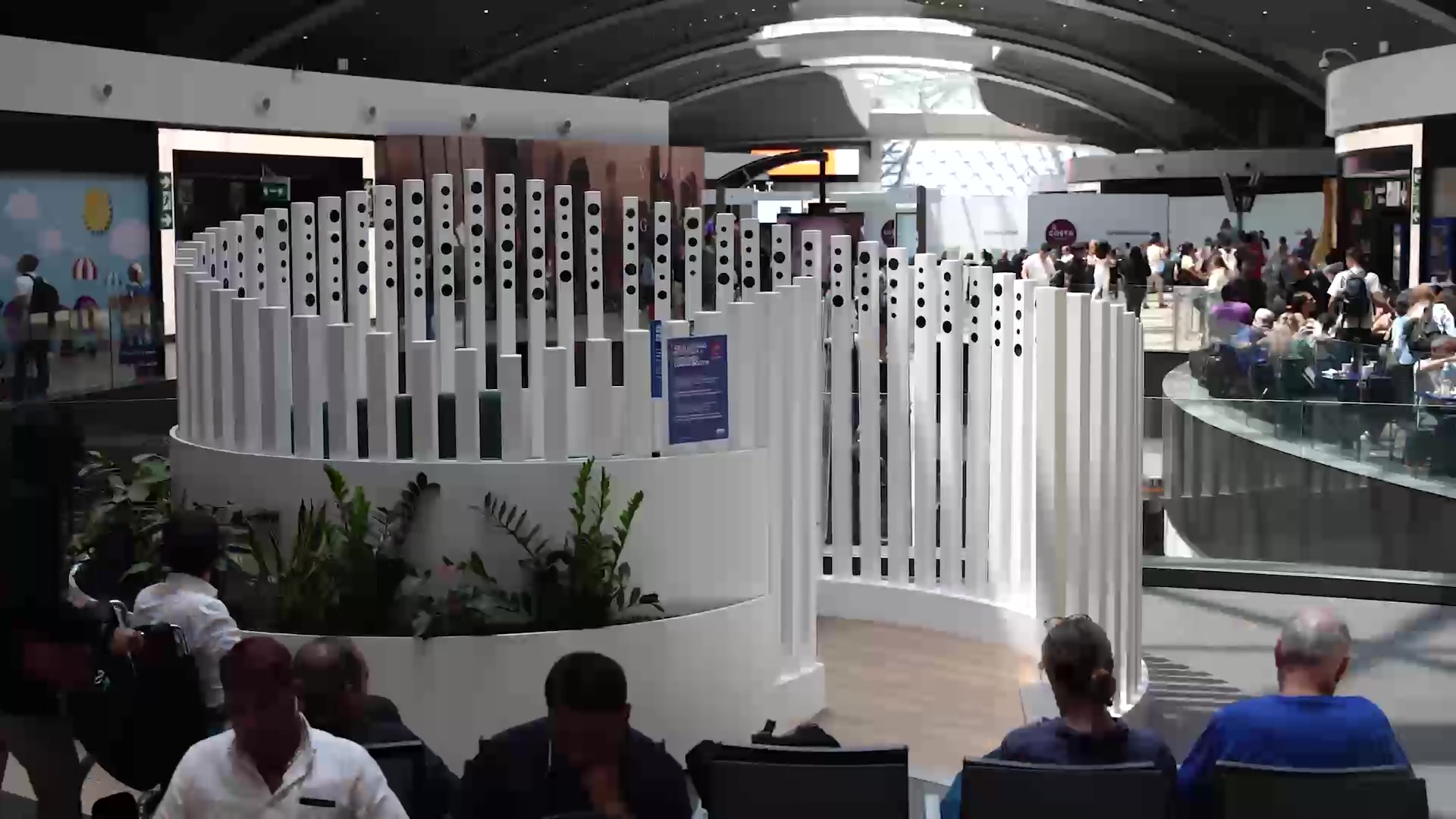 Vista panoramica dell’area Dining Booth con sedute, piante e persone in attesa