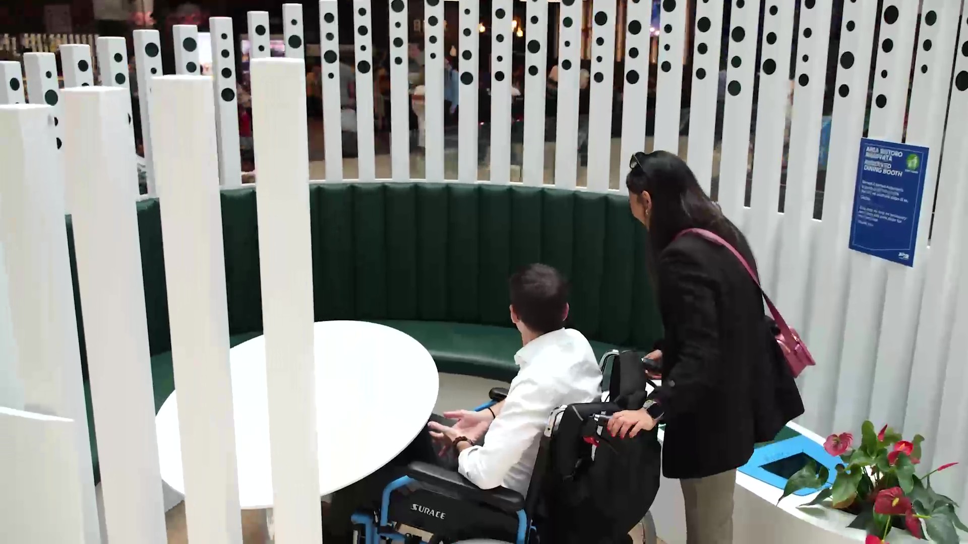 Area Dining Booth con tavolo, sedute e persona in sedia a rotelle accompagnata