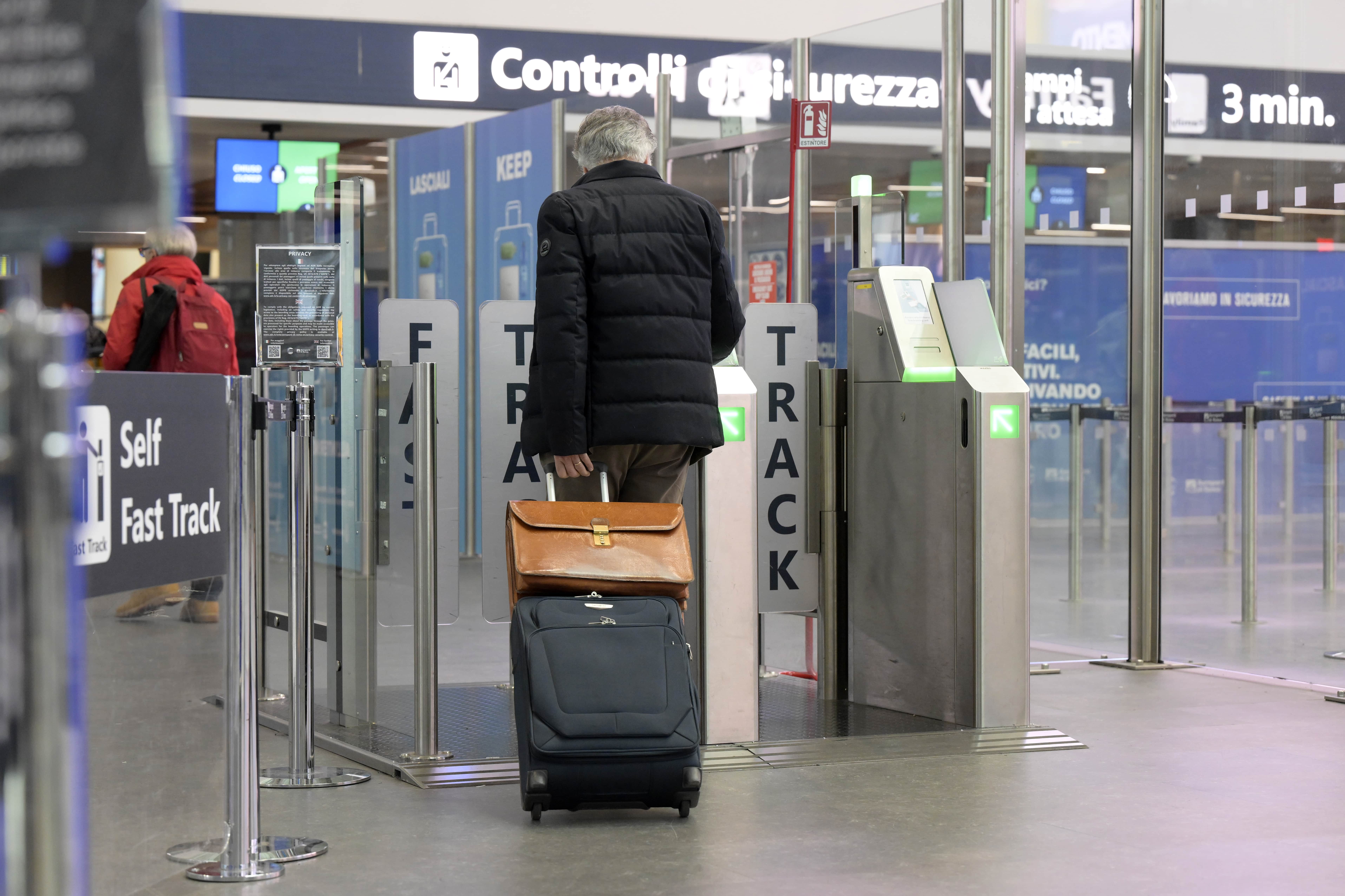 Passeggero con bagaglio ai varchi Fast Track per i controlli di sicurezza in aeroporto